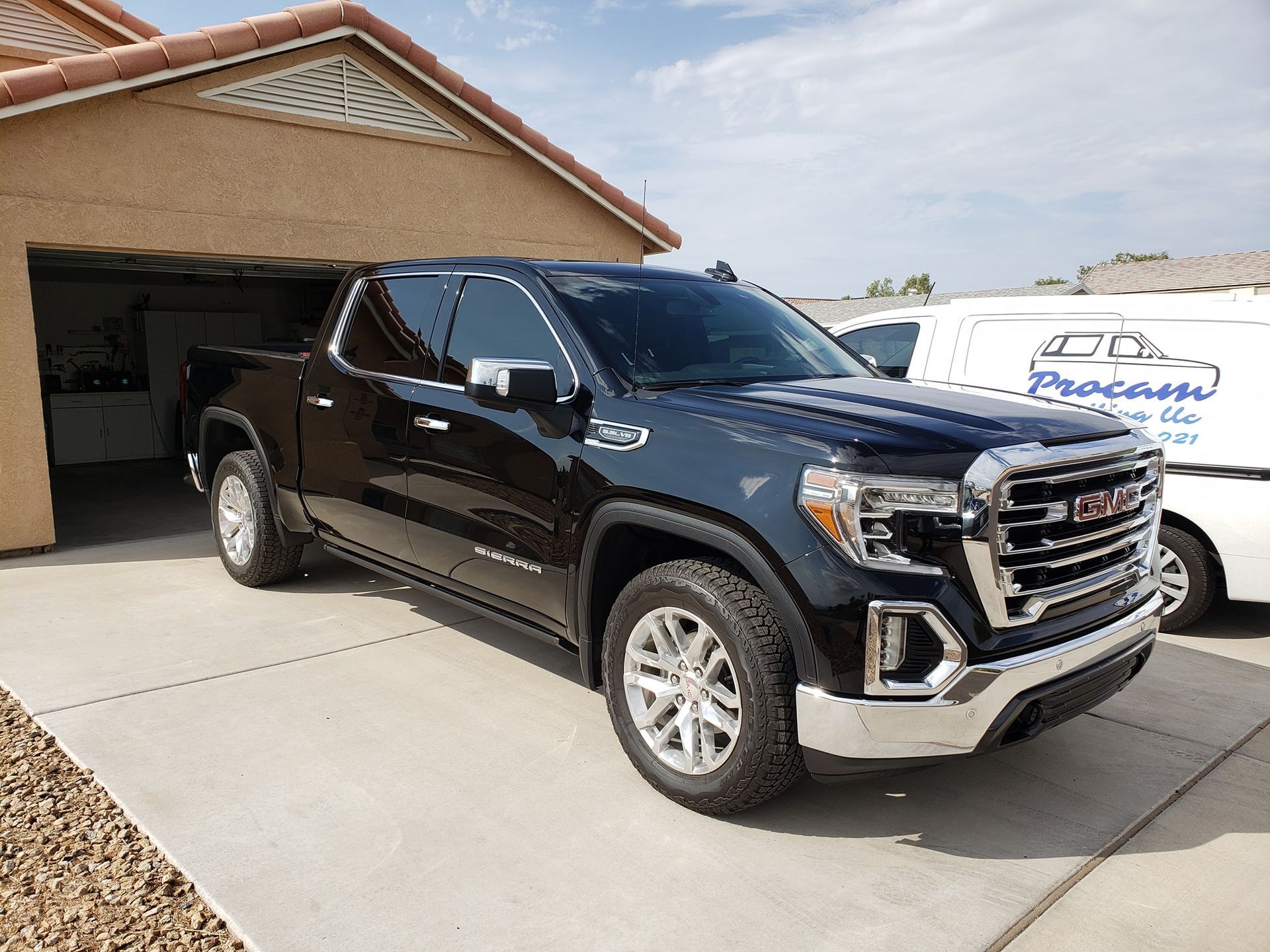 a black gmc sierra pickup truck is parked in front of a garage .