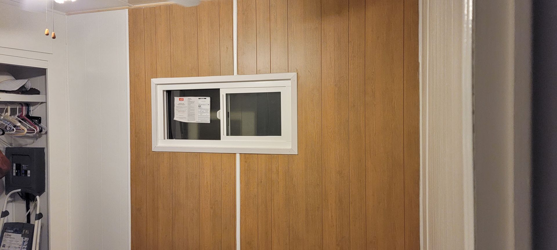 A closet with wood paneling and a window on the wall.