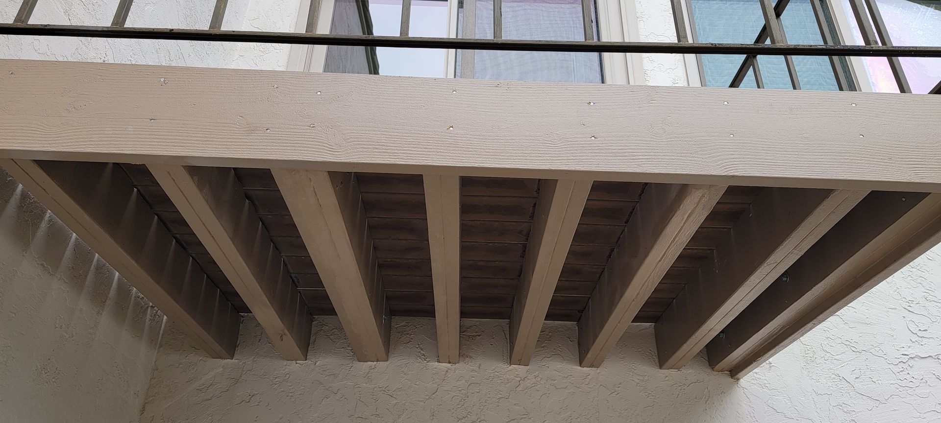 A wooden balcony with a railing on the side of a building.