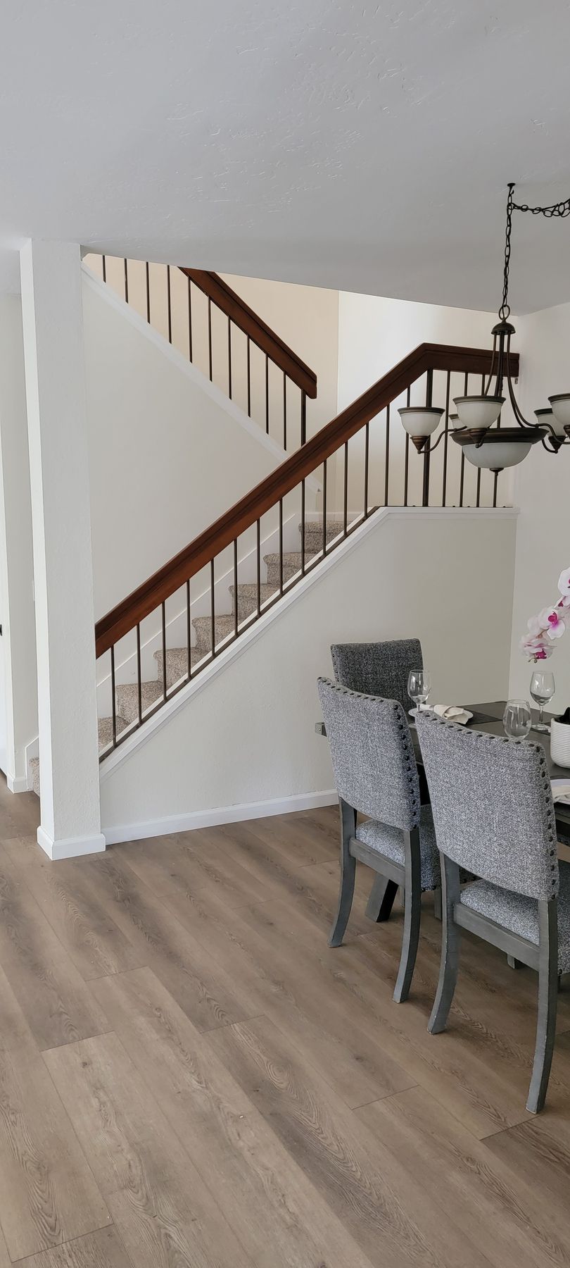 A dining room with a table and chairs and stairs.