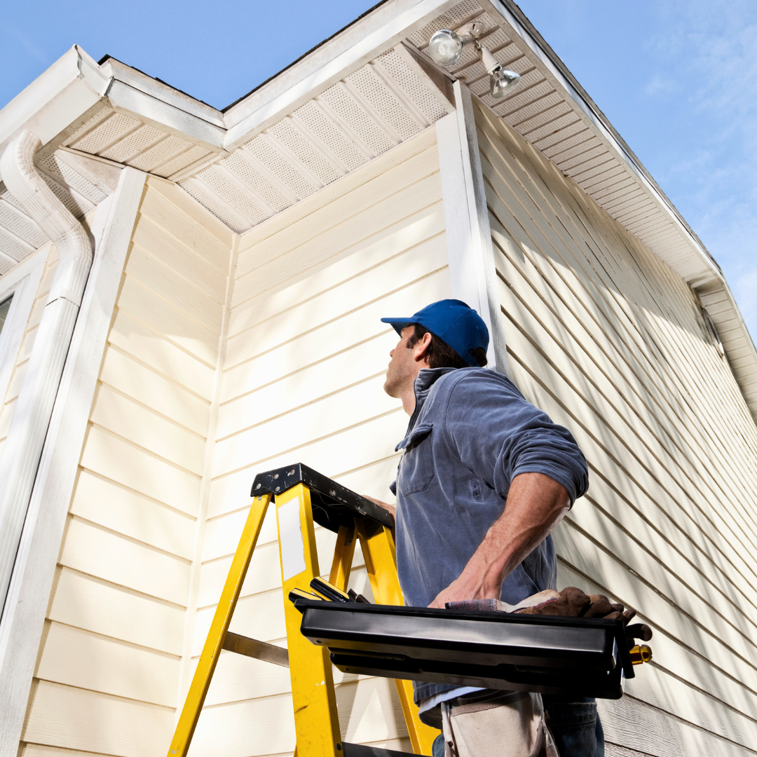 A man standing on a ladder in front of a house