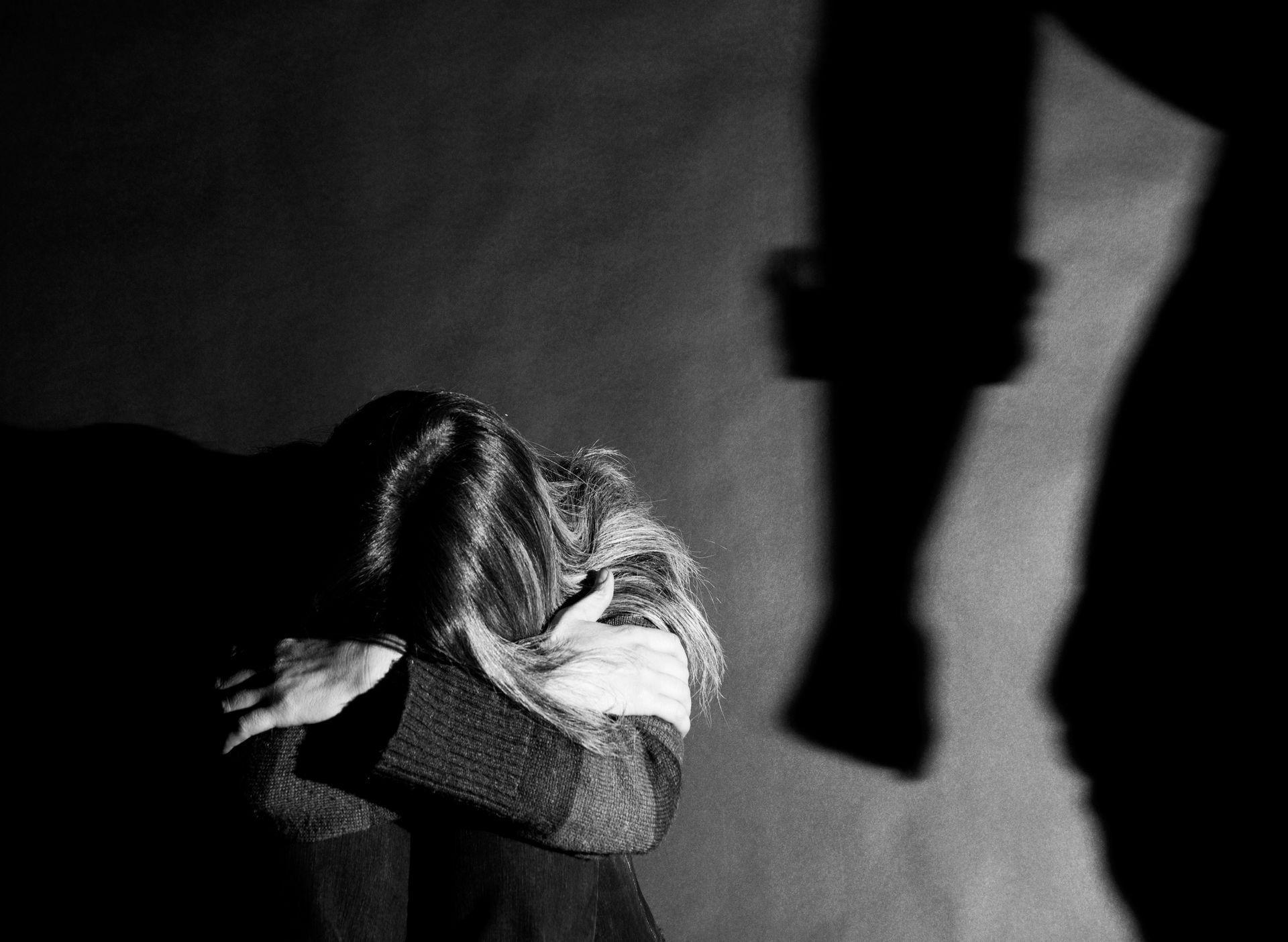A woman is sitting on the ground with her head in her hands in a black and white photo.