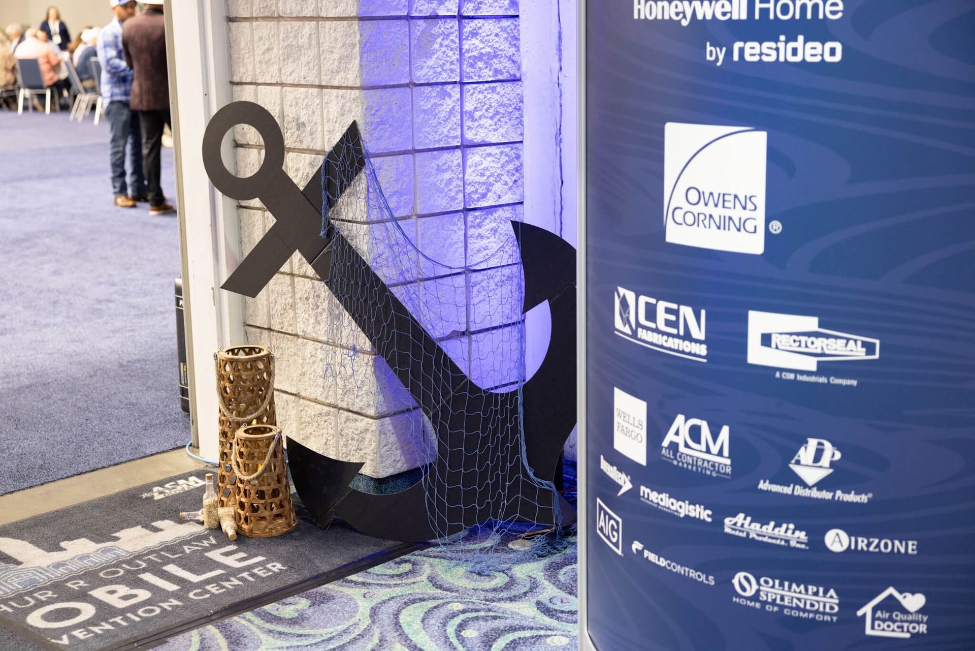 Large black awareness ribbon beside sponsor banners at a conference entrance