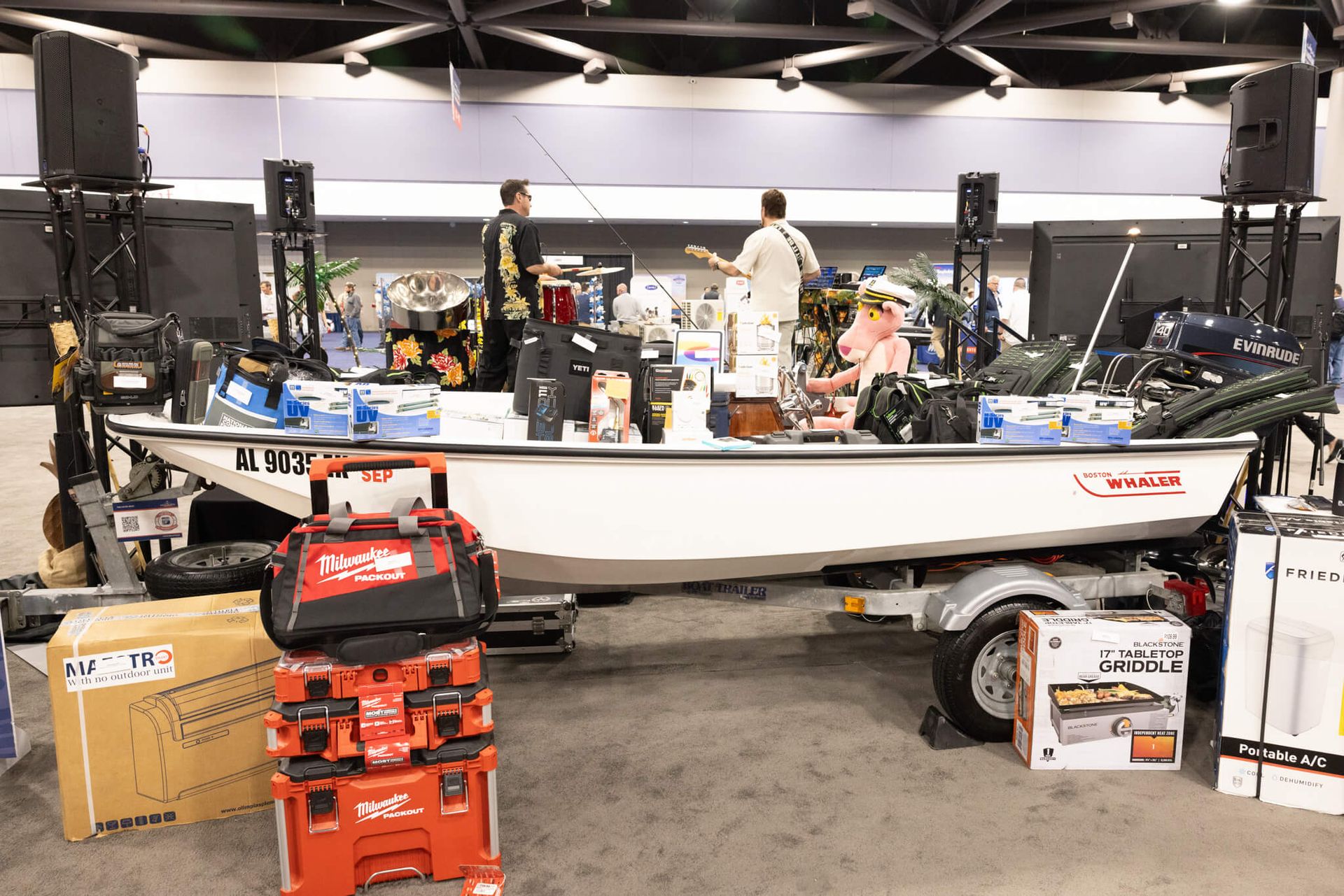 Busy indoor boating exhibit with a small white boat and people around displays in a showroom