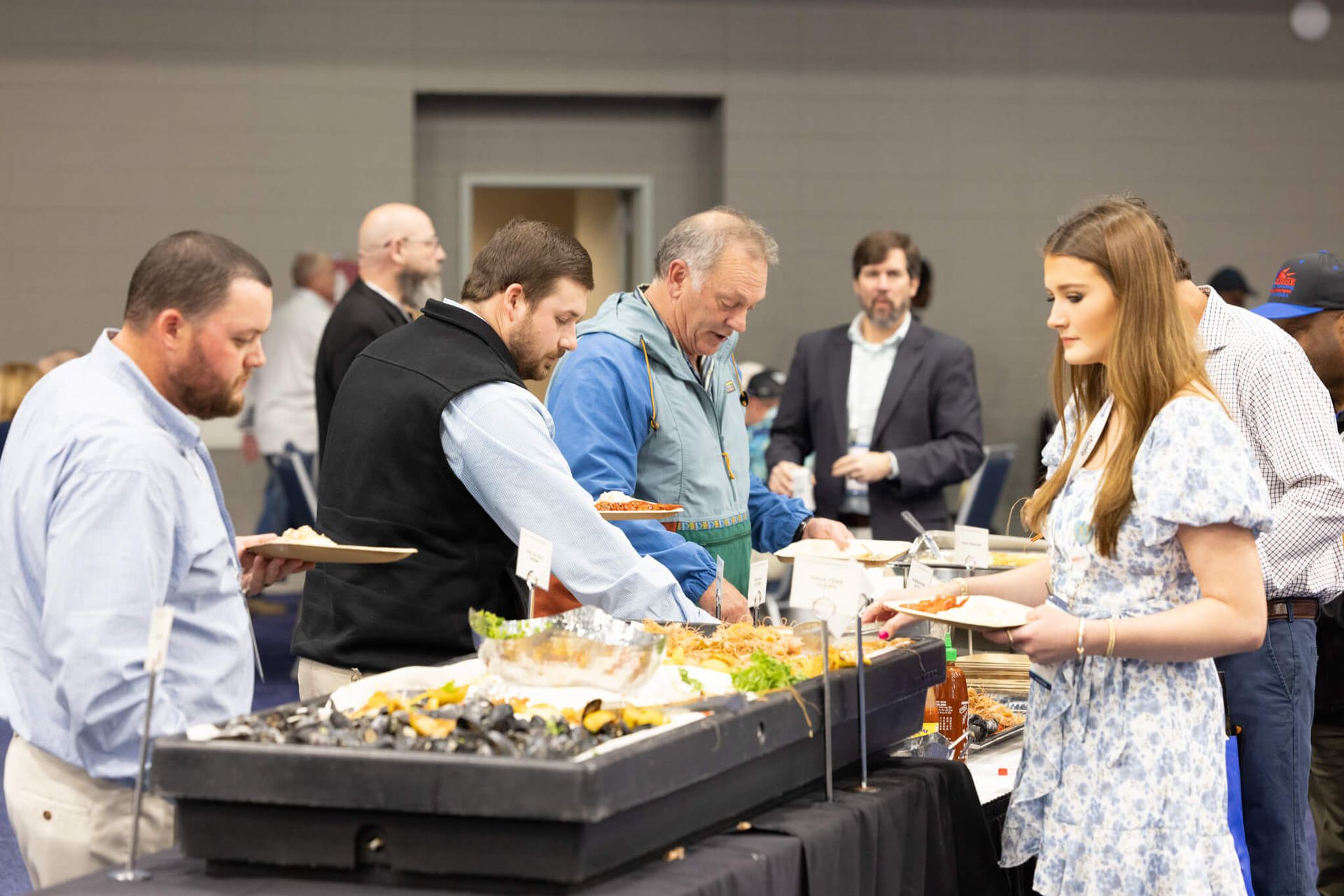 People serving buffet food at a table during a social event