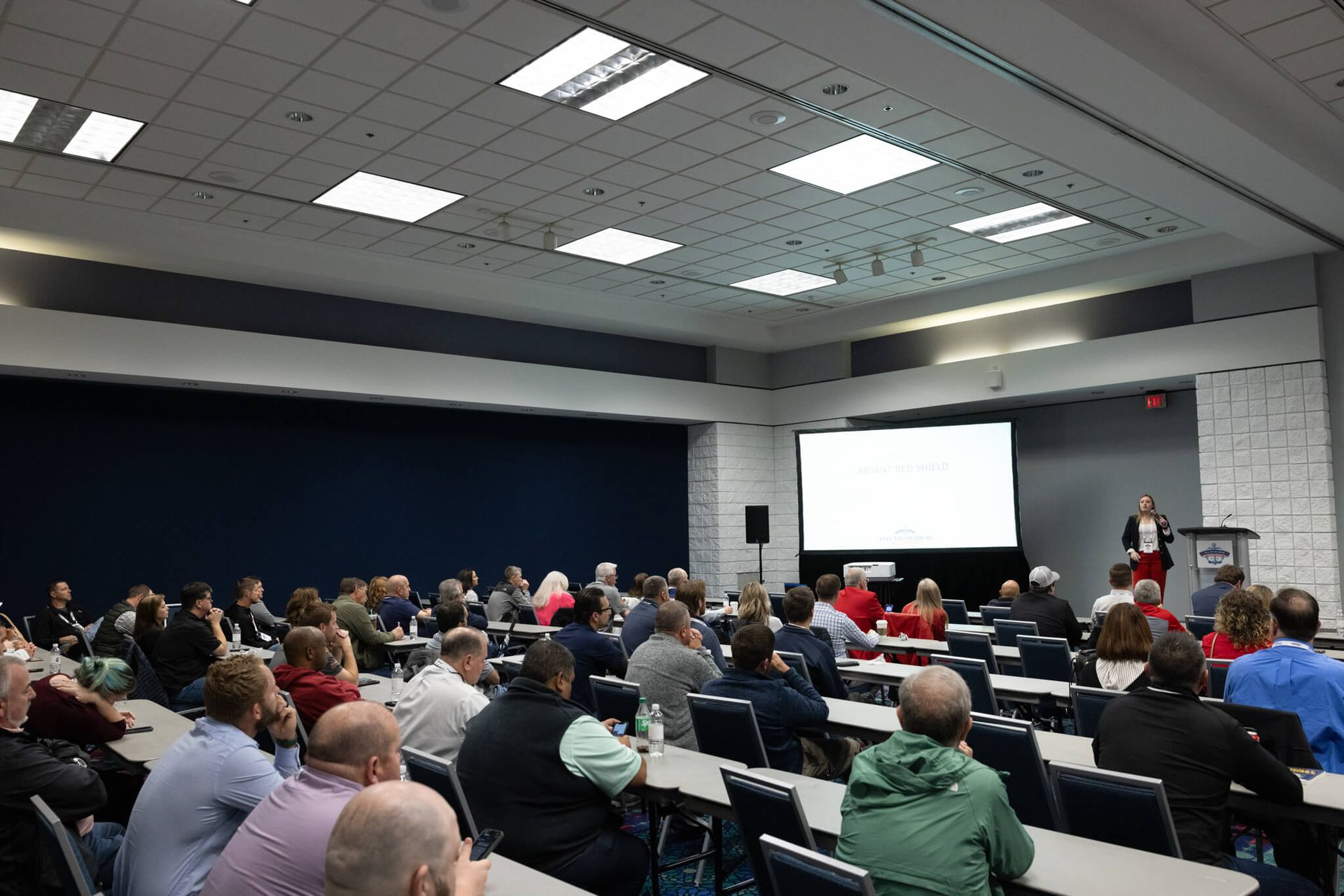 Audience seated in a lecture hall watching a presentation on a large screen