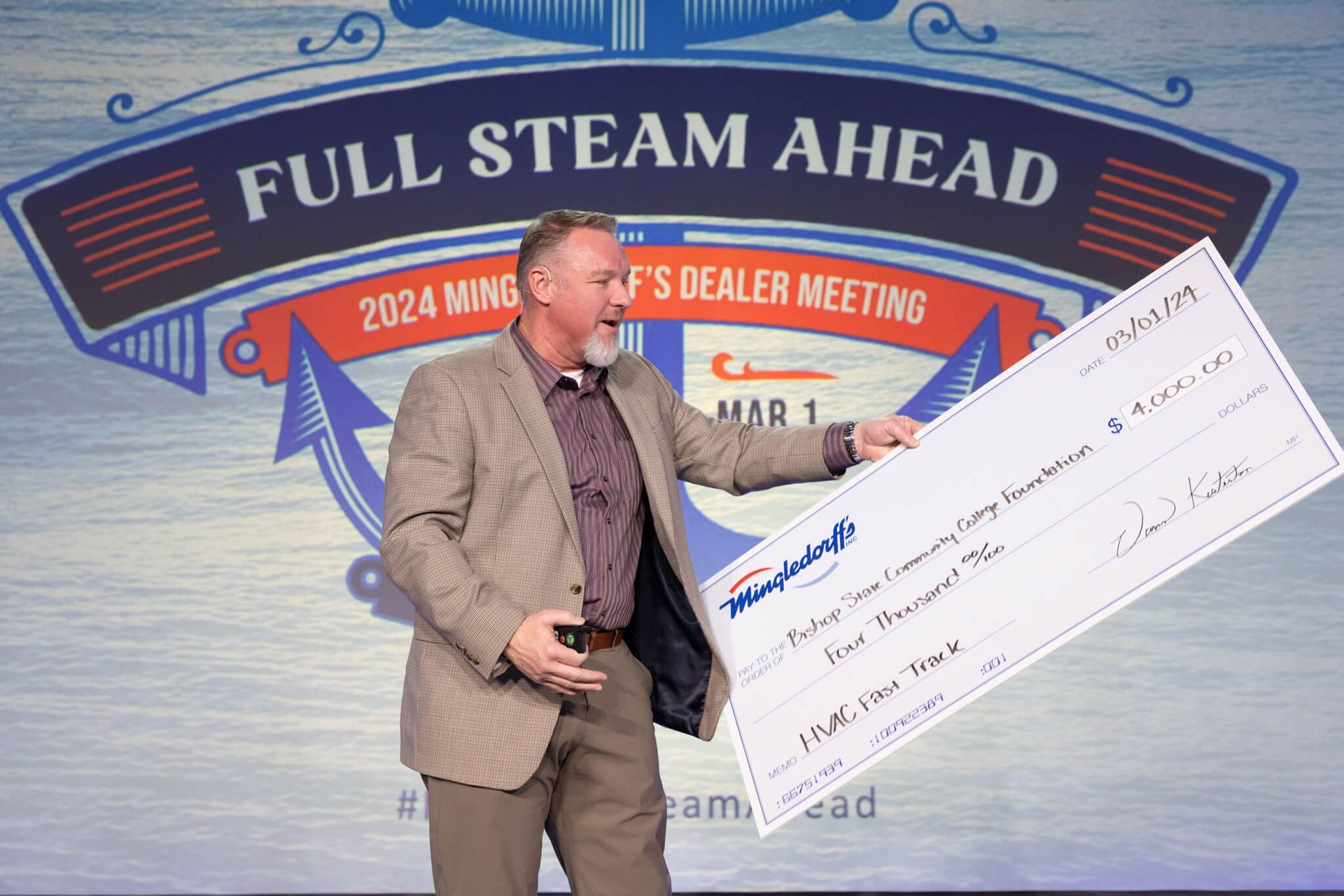 Man holding an oversized check at a Steam Ahead dealer meeting stage