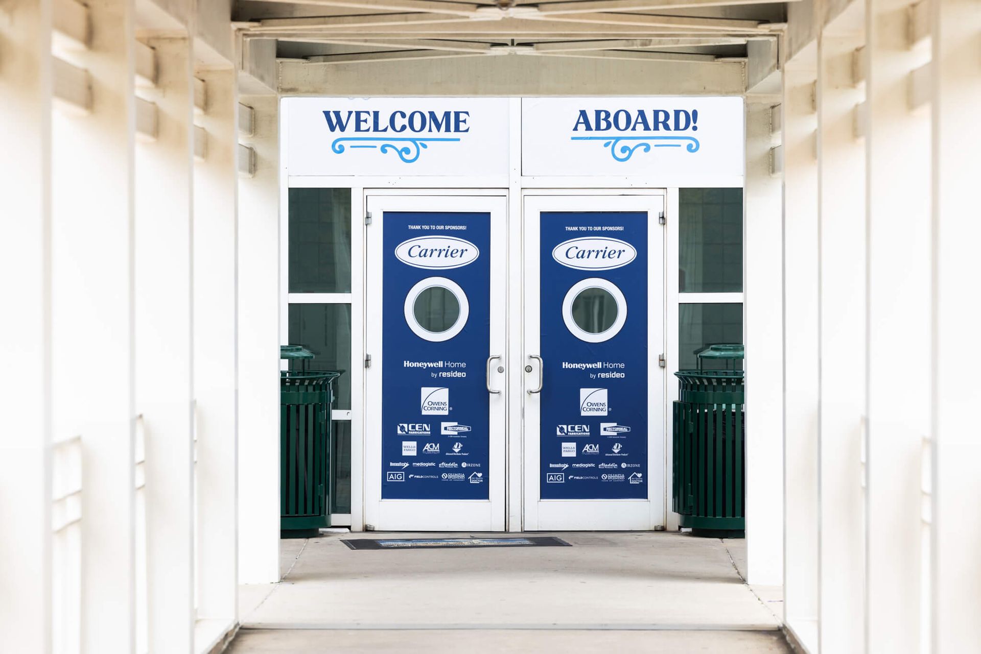 Blue welcome and aboard doors at a building entrance with white walls and columns