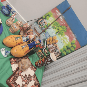 Handmade crafts and gourds arranged on a green mat beside a painted wall and gray curtains