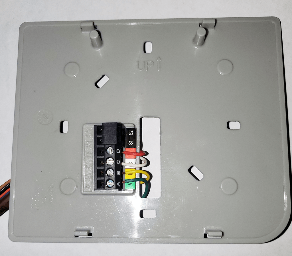 Gray electrical wall plate with wiring terminals and colored wires exposed on the back