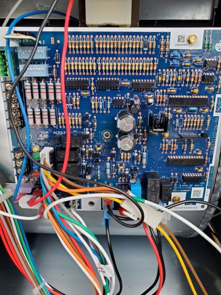 Blue electronic circuit board with many wires and connectors inside an open device case