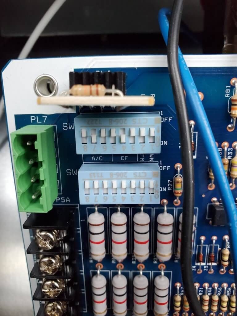 Close-up of a blue circuit board with connectors, resistors, and terminal blocks.