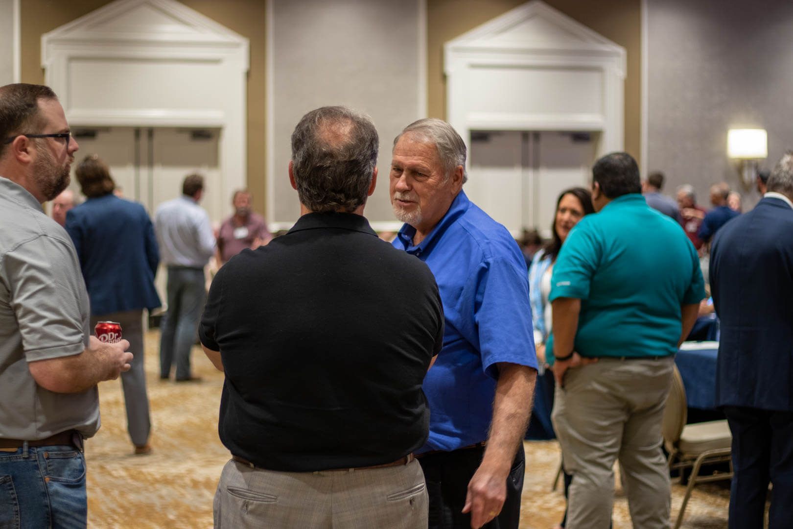 People standing and talking at a conference reception in a hotel ballroom