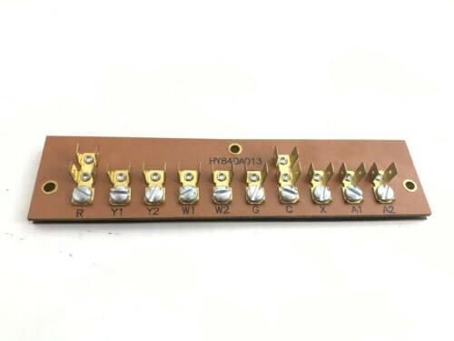 Row of small electrical terminal lugs mounted on a brown circuit board with screw holes