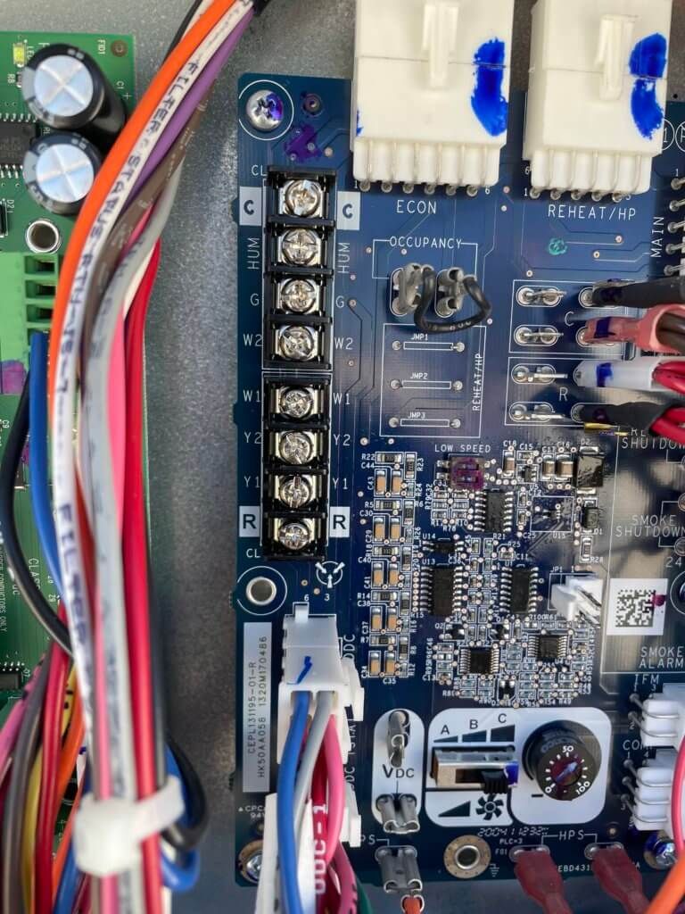 Close-up of a blue circuit board with connectors, wires, and electronic components.