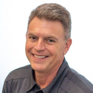 Smiling man in a gray shirt against a white background