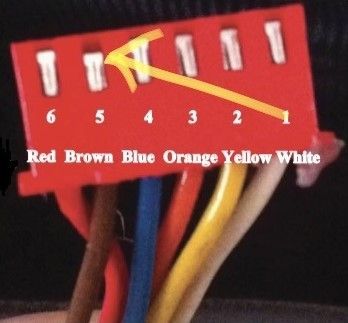 Close-up of a red connector with colored wires and numbered pins labeled red, brown, blue, orange, yellow, white.