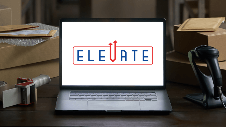 Laptop on a desk displaying the word “ELEVATE,” with boxes and a handheld scanner nearby.