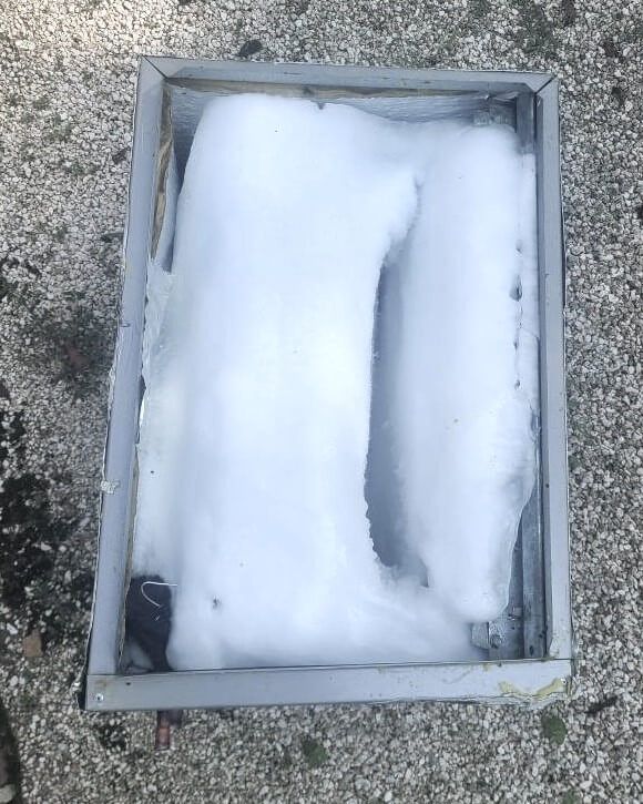 Snow packed inside a rectangular metal frame on a gravel surface.