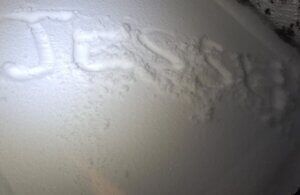 Close-up of white frosty snow or ice on a surface with faint embossed lettering