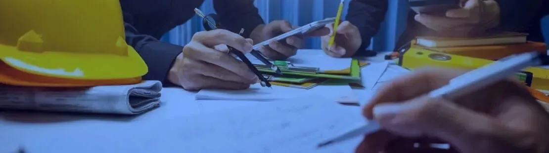 Hands writing with pencils and markers on papers at a table