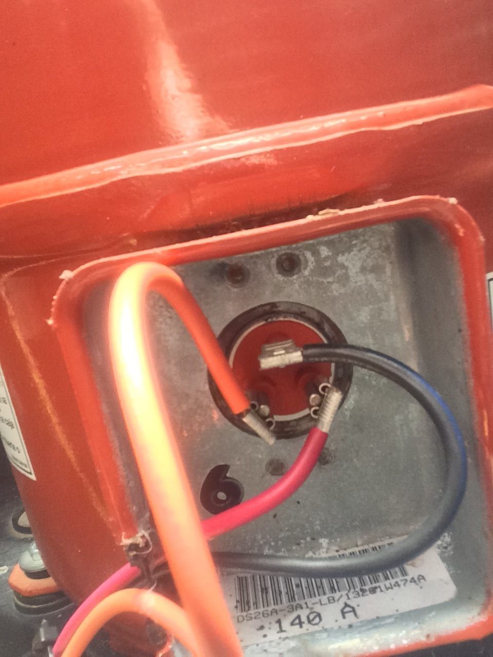 Close-up of red electrical panel wiring with black and red wires connected to a metal terminal.