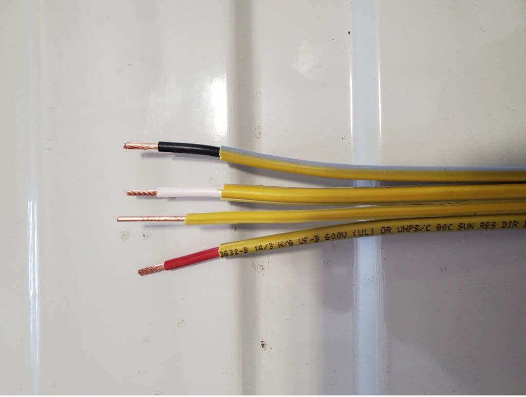 Four stripped electrical wires with colored insulation ends on a white surface