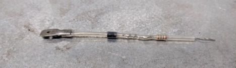 Long metal rod with a black handle lying on a concrete surface