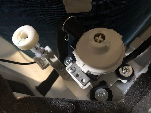 Close-up of a car seat mechanism with a gray adjustment knob and metal bracket