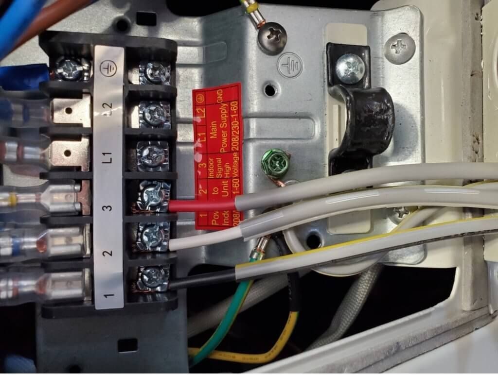 Electrical terminal block with labeled wires inside a metal appliance panel