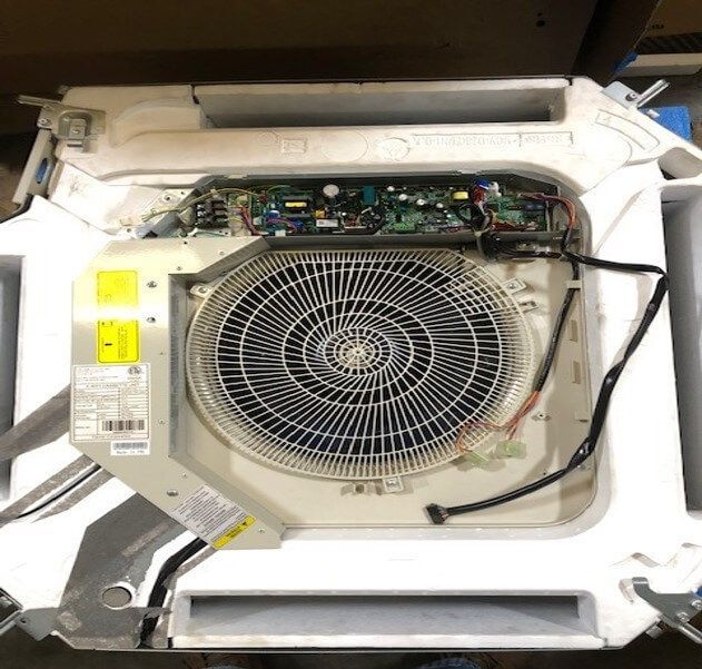 Open appliance with exposed fan and circuit board inside a white casing