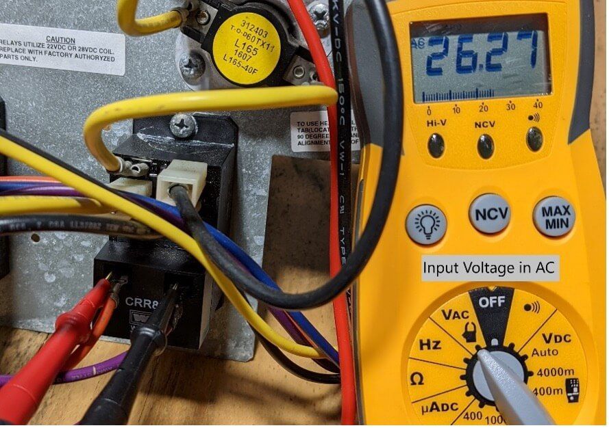 Digital multimeter reading 26.27 beside yellow wires and an electrical connection panel