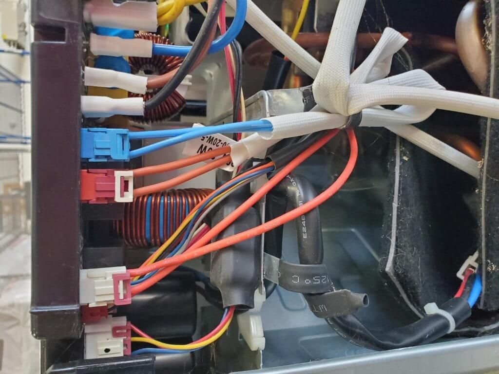 Wiring harness and colored connectors inside an electrical control panel with a cooling fan.