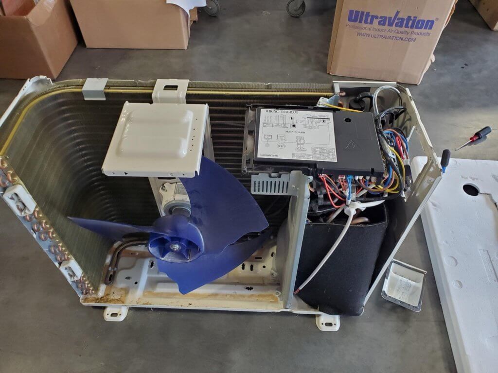 Open box fan with blue impeller, wiring, and control box on a workshop floor