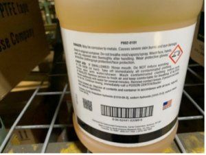 White chemical jug on a store shelf with hazard label and barcode