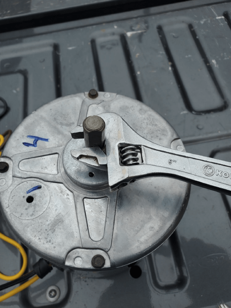 Close-up of a metal motor or gearbox with a wrench on the shaft and wires attached