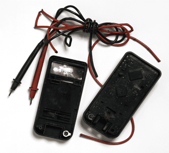 Black electrical tester with red probes and bundled wires on a white background