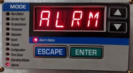 Close-up of a control panel showing red “ALRM” display with Escape and Enter buttons