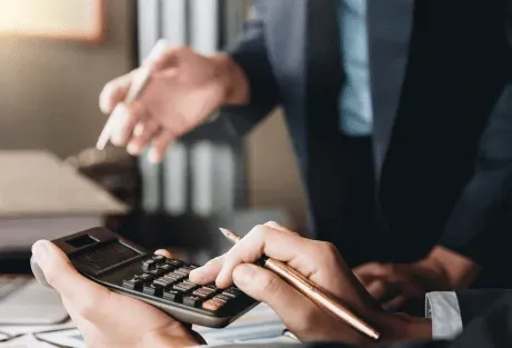Close-up of hands using a calculator and pen during a business meeting