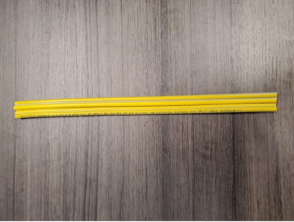 Two yellow plastic straws lying horizontally on a gray wood-textured surface