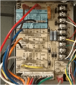 Close-up of a wired electrical control board with labeled terminals and colored wires.