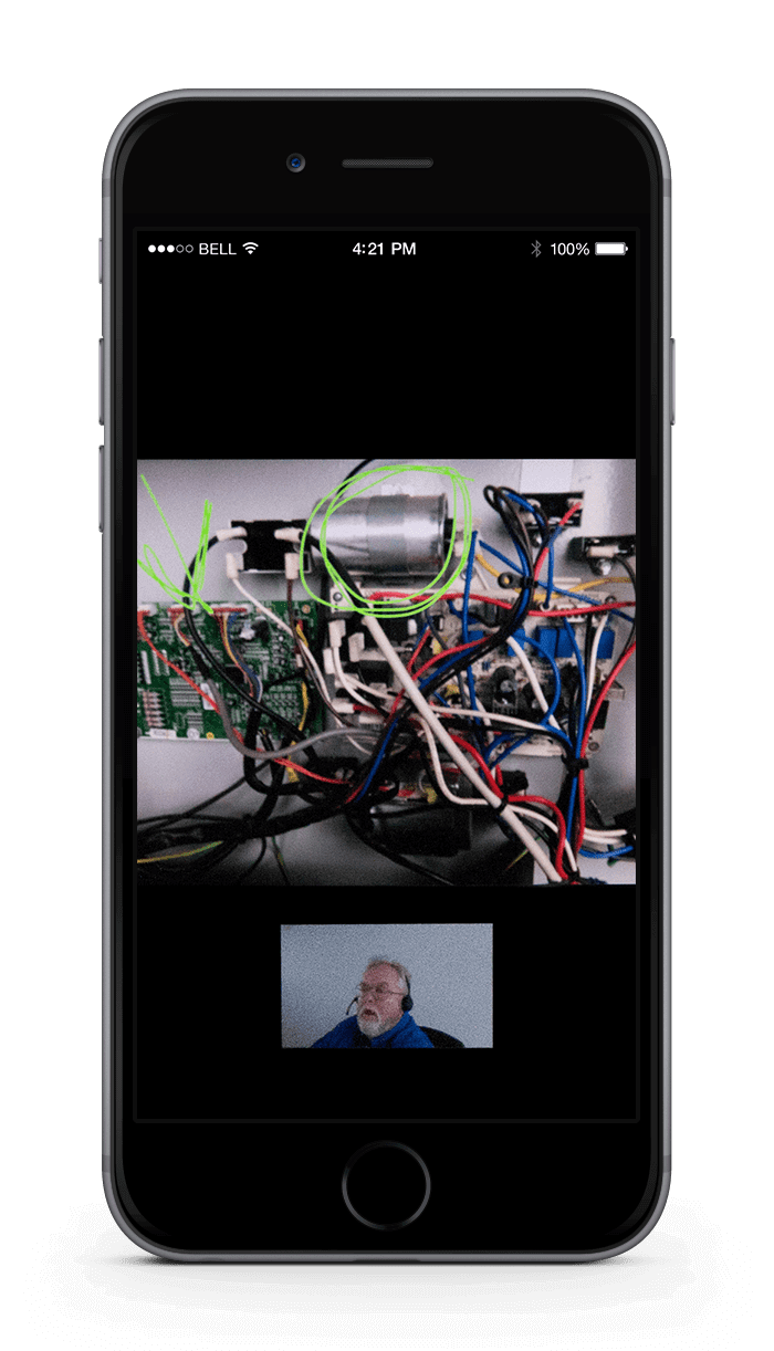Smartphone screen showing a cluttered electronics setup and a small video call window with a person speaking