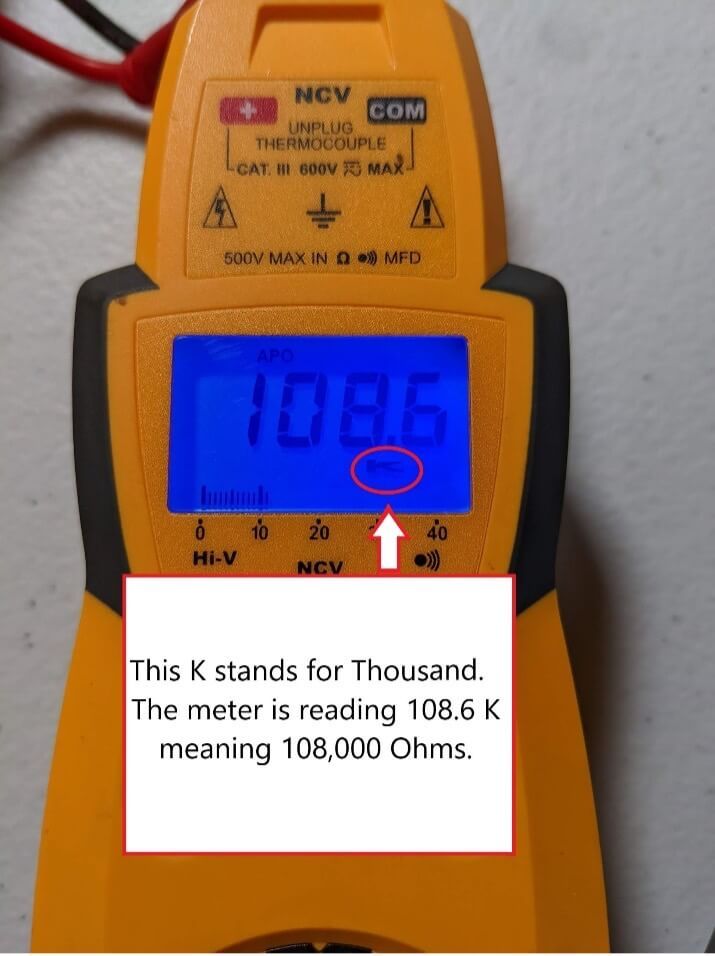 Yellow digital multimeter displaying 108.6 KΩ on blue backlit screen, with note explaining K means thousand.