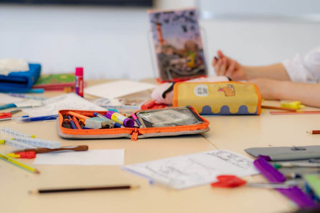 Table with open notebooks, pencil cases, and scattered school supplies in a classroom or study area