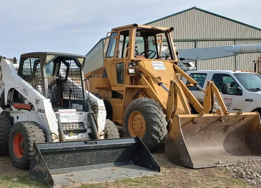 A bobcat and a case loader are parked next to each other