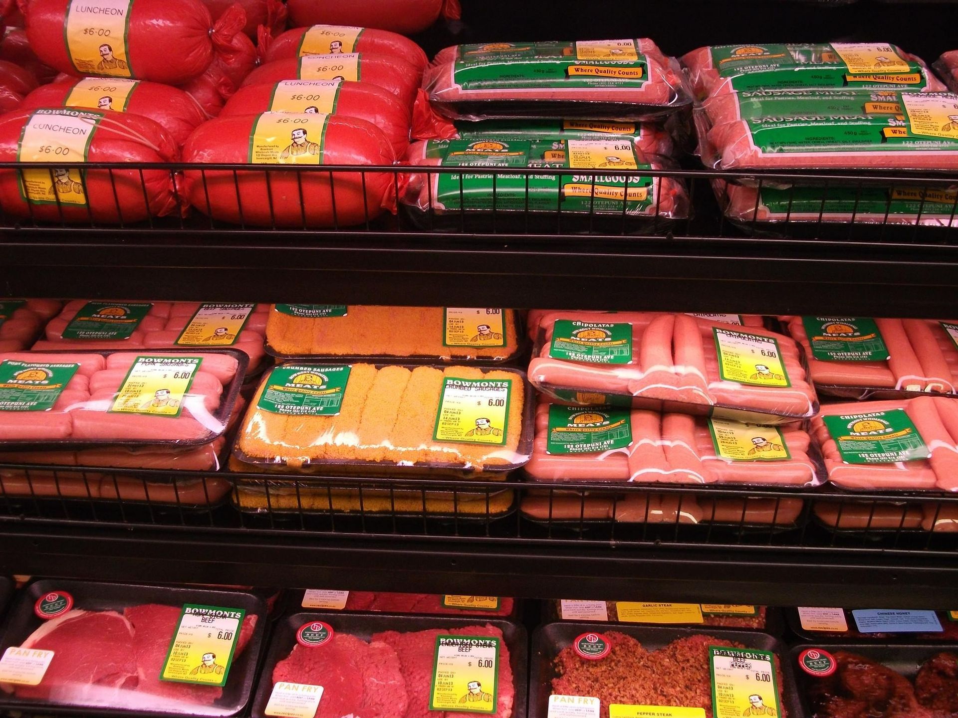 Meat products in various packages on supermarket shelves.