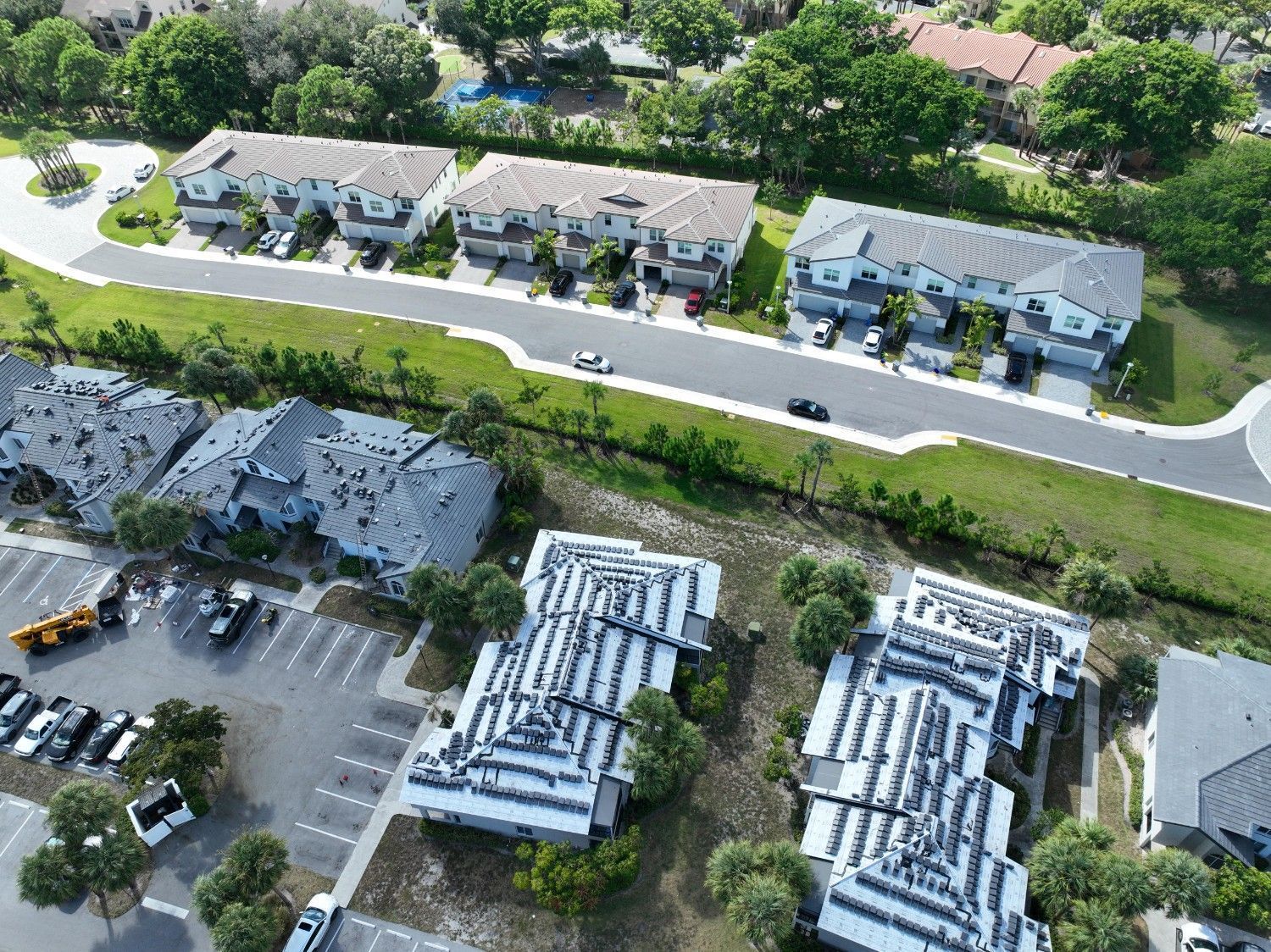 Aerial view of a residential complex with apartment buildings, roads, parking lots, and trees.