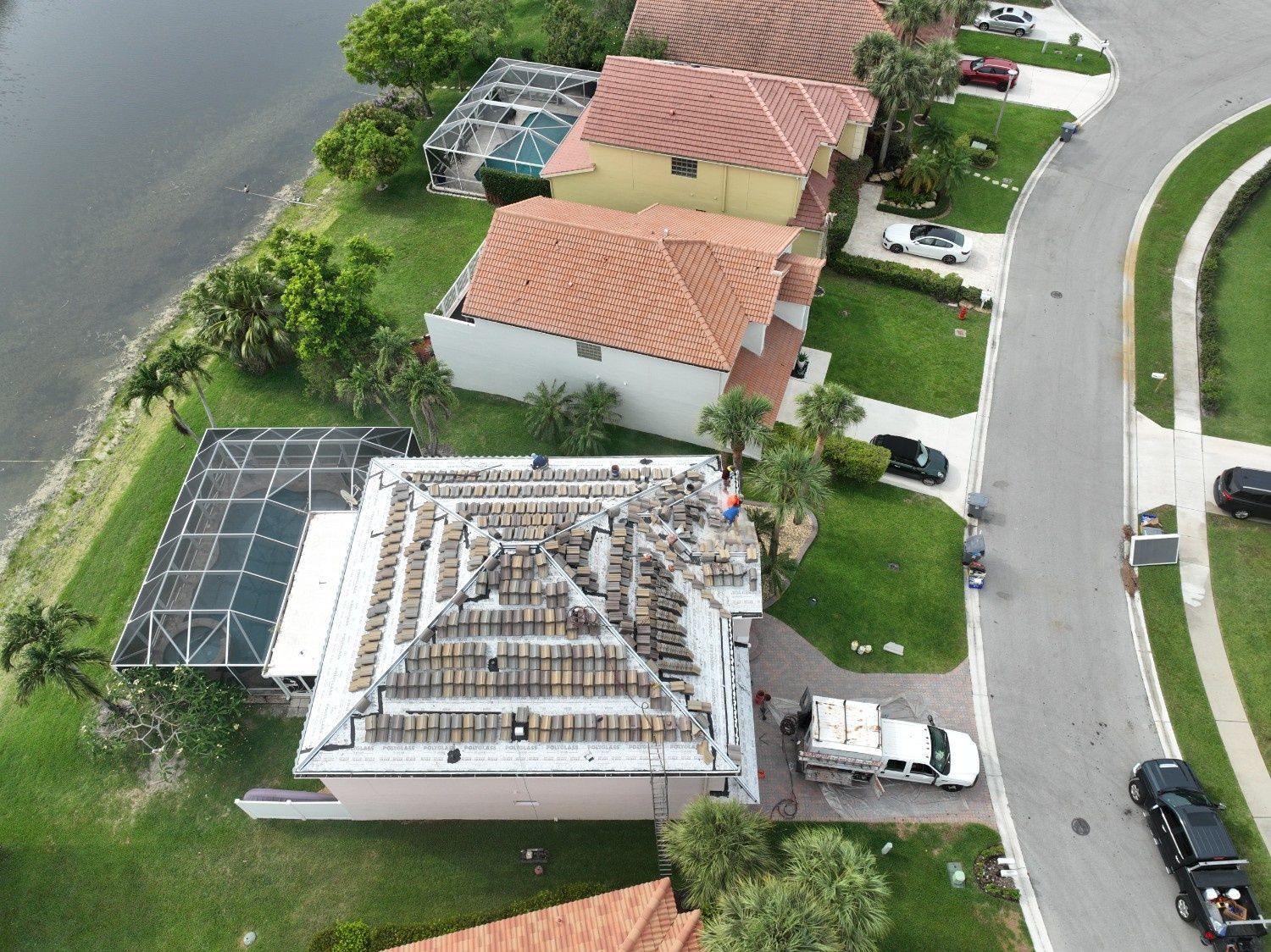 Aerial view of houses by a canal, with a roof under construction and solar panels nearby.