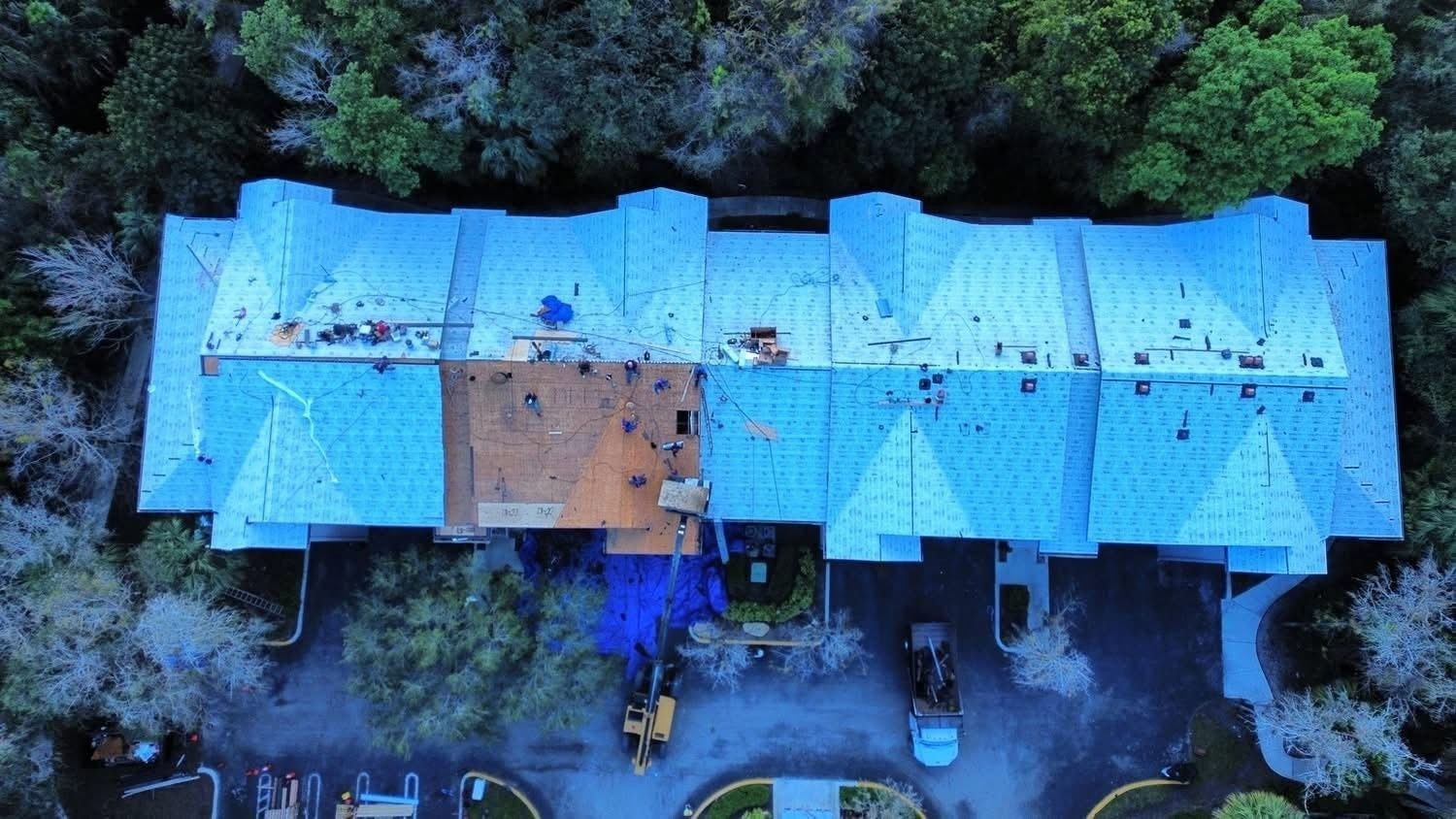 Aerial view of a blue-roofed residential building surrounded by trees.
