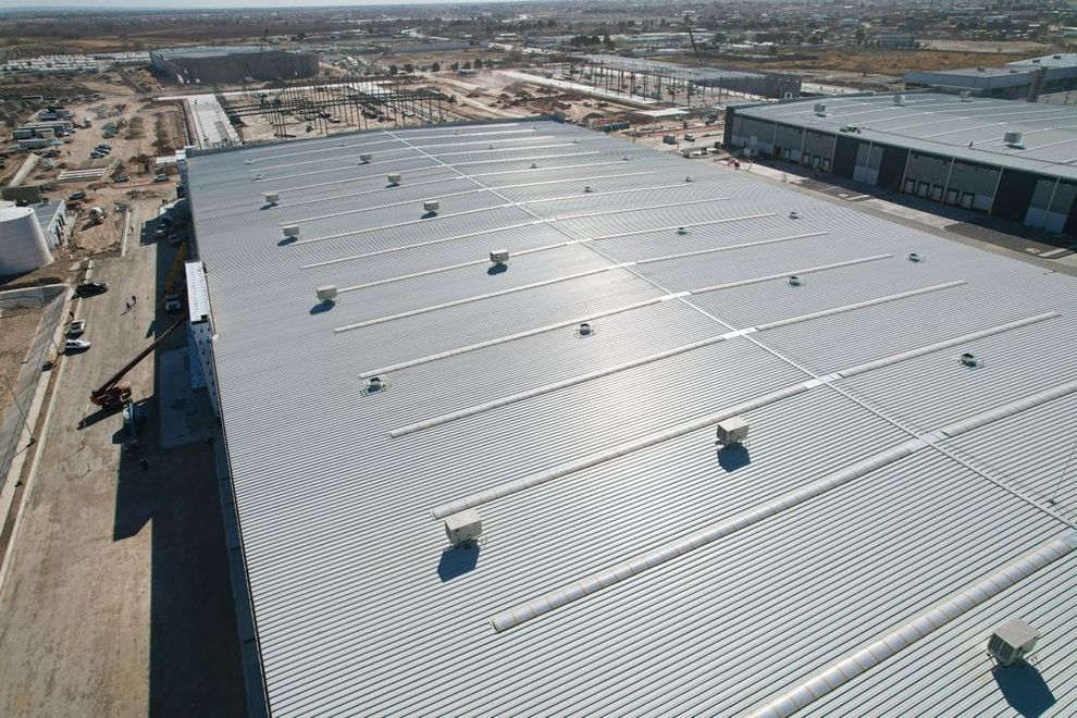 Aerial view of a large white industrial warehouse roof with vents in a desert landscape